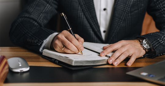 adult male businessman writing on a notepad